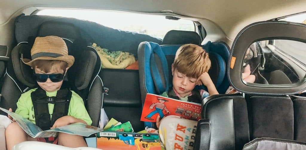 2 children reading books during road trip