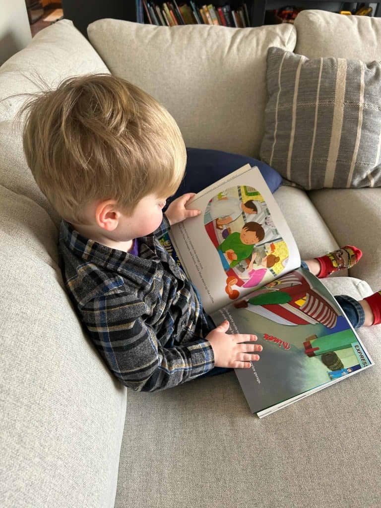 toddler reading book on couch