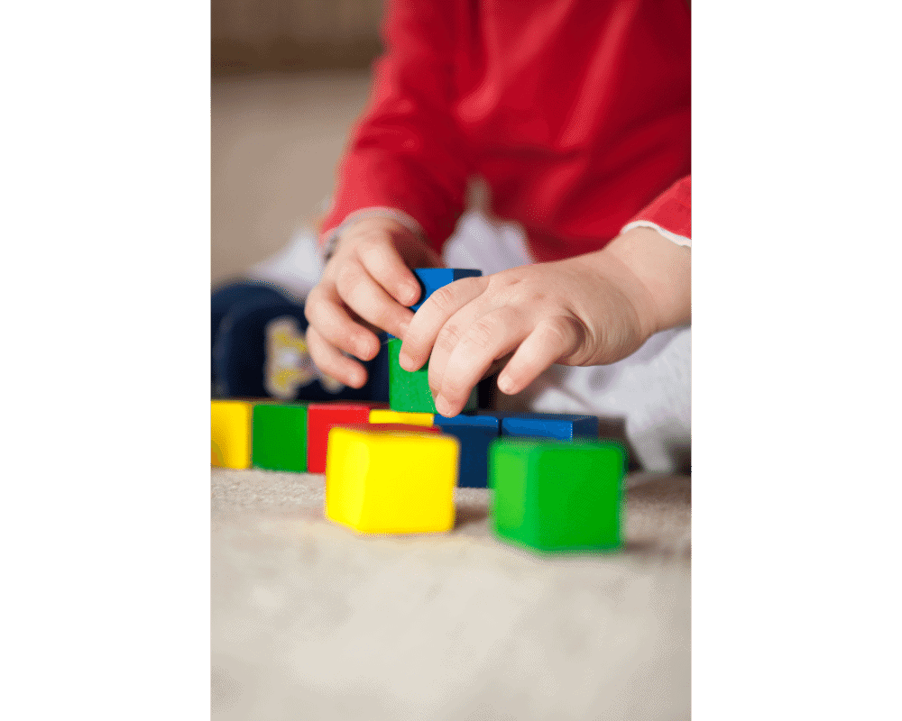 Toddler playing with colorful blocks, fine motor development