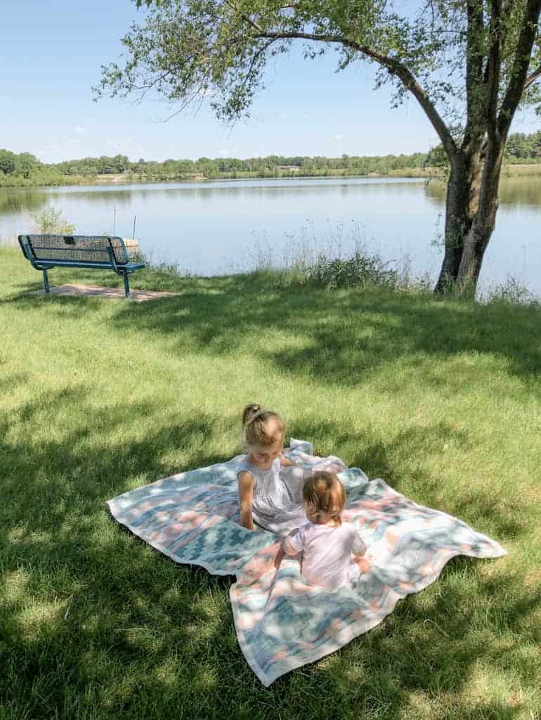 Two children on a blanket having a picnic at the park in springtime.