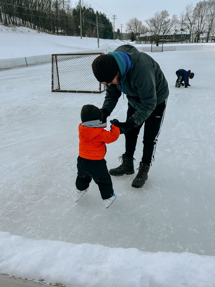 dad ice skating with toddler holding hands