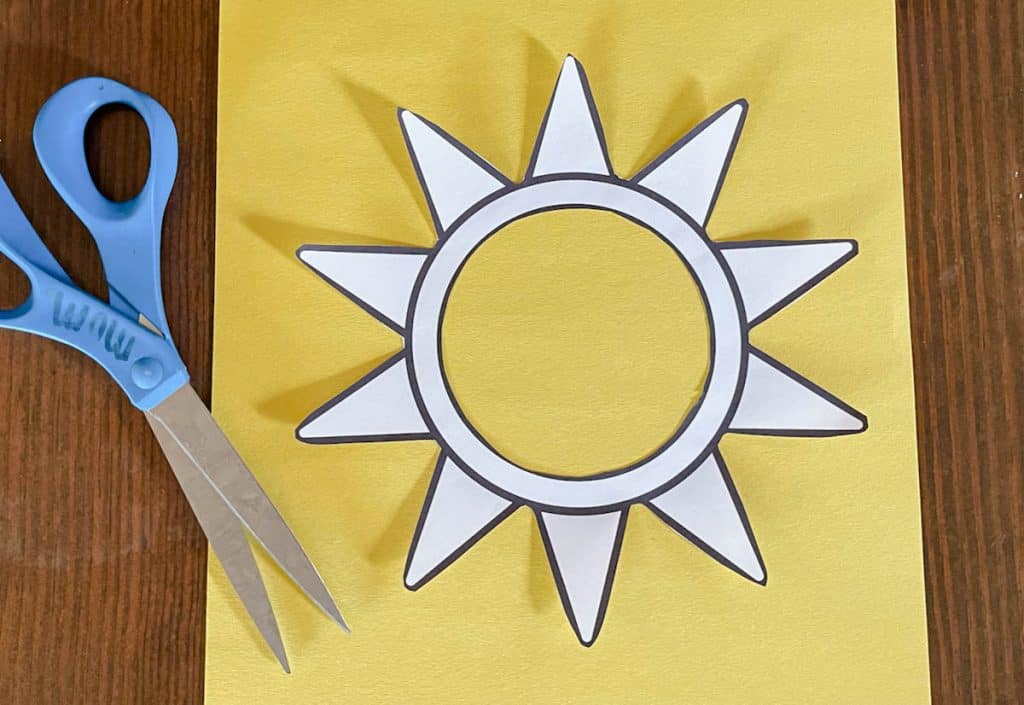 scissors and sun craft template and yellow construction paper on table