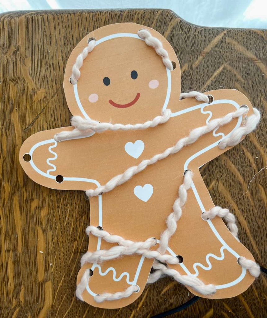 Gingerbread man lacing card laying on table that is wrapped up and looks like a mummy