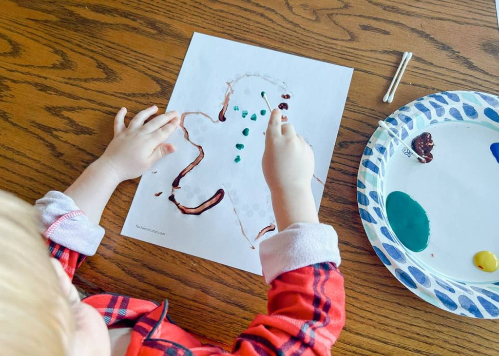 child using q tip and paint to create their gingerbread man