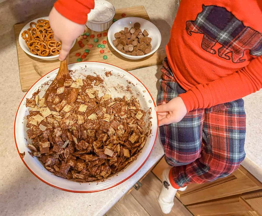 child stirring Chex and peanut butter/chocolate mixture together