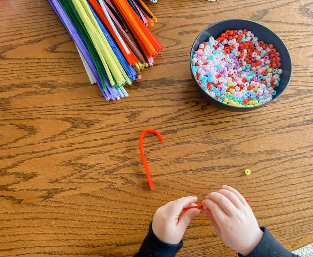 child stringing on bead to candy cane pipe cleaner