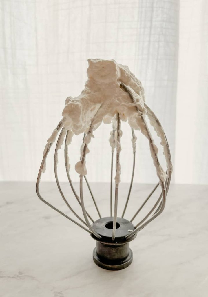 whipped cream on a mixing whisk sitting on the counter