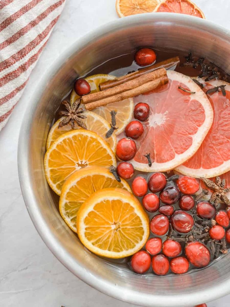 saucepan filled with oranges, grapefruits, cloves, and cranberries