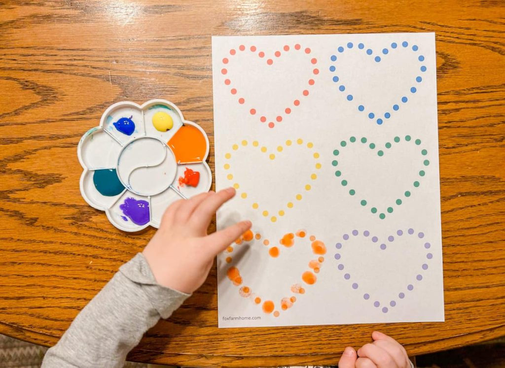 Child painting with fingerprint heart printable with paint next to them