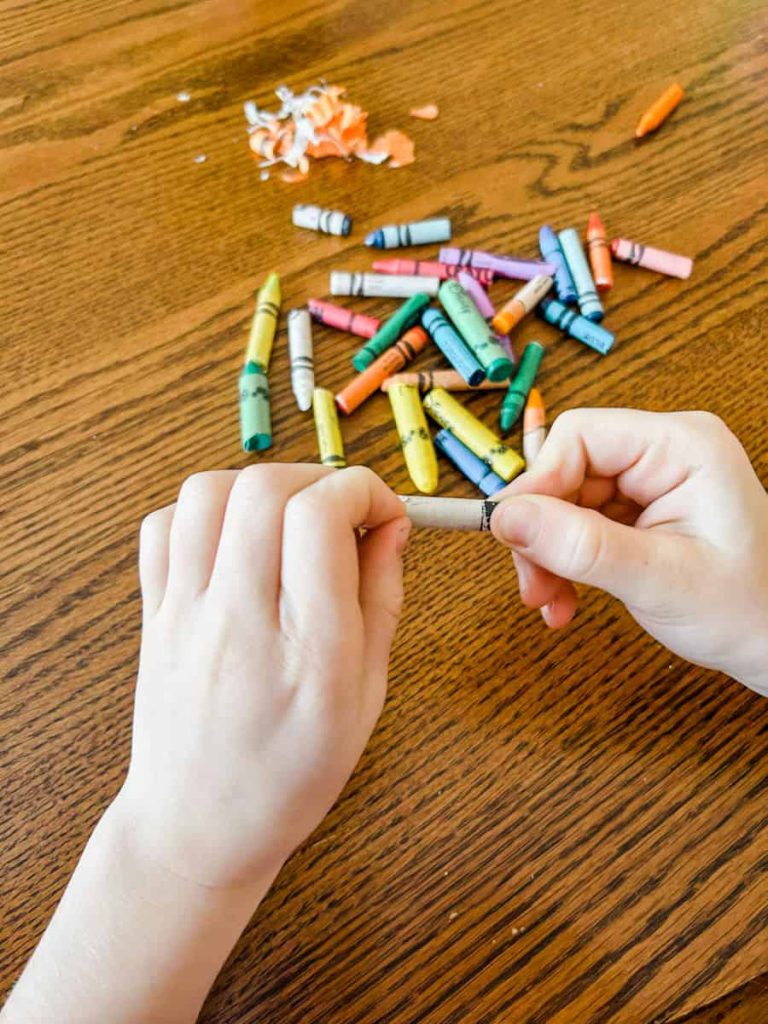 child taking paper off of crayons