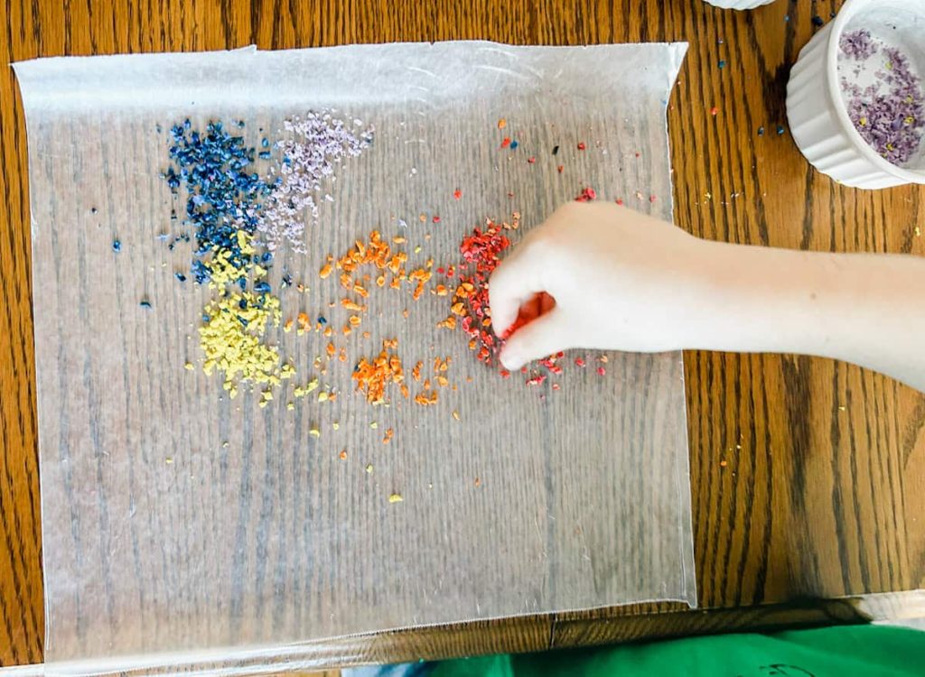 child putting crayon shredding on his wax paper