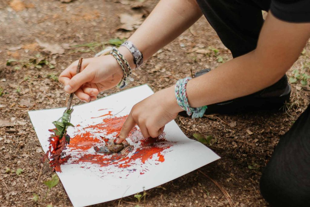 child painting with DIY nature paint brush
