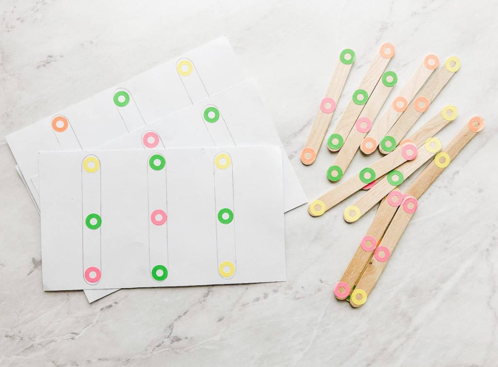 paper and popsicle sticks sitting on table with sticker patterns on them