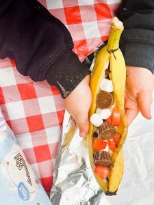 child holding banana boat with toppings in it