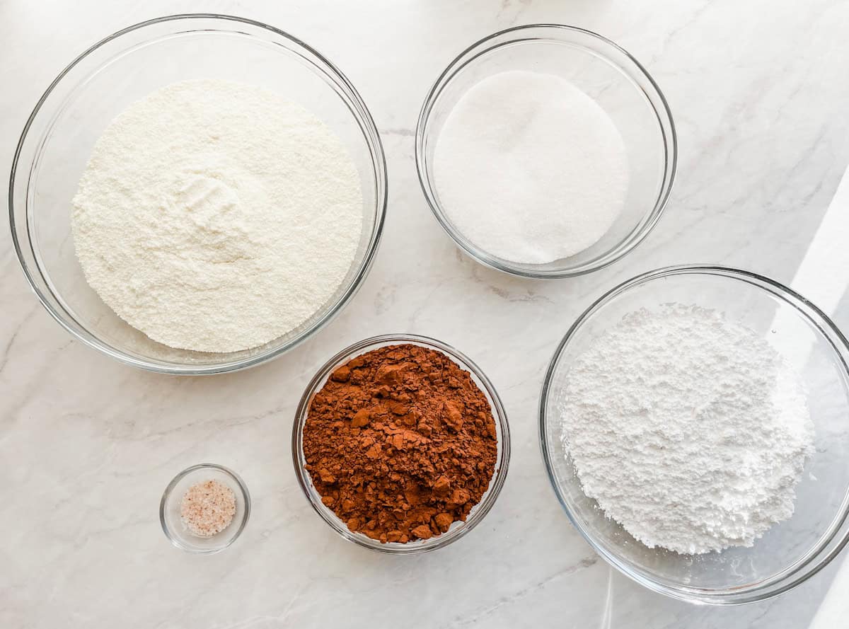 The ingredients for hot chocolate mix recipe sitting in bowls on the counter.