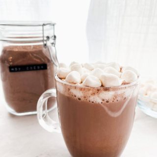 cup of hot chocolate on the counter with hot cocoa mix in the background
