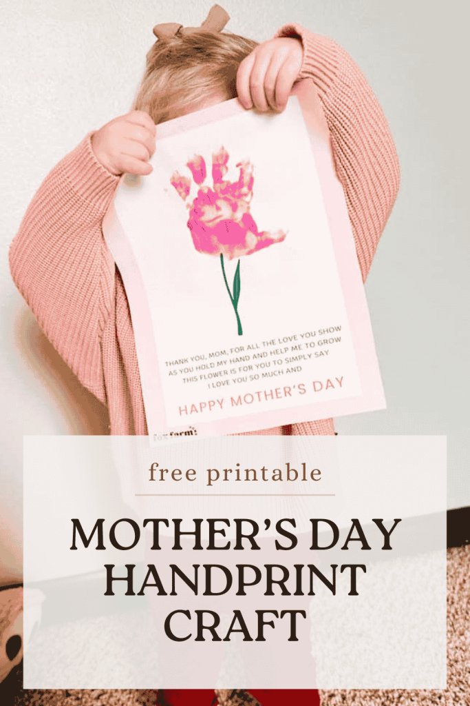 Pinterest pin for the Mother's Day Handprint Craft with child in pink sweater holding her created card