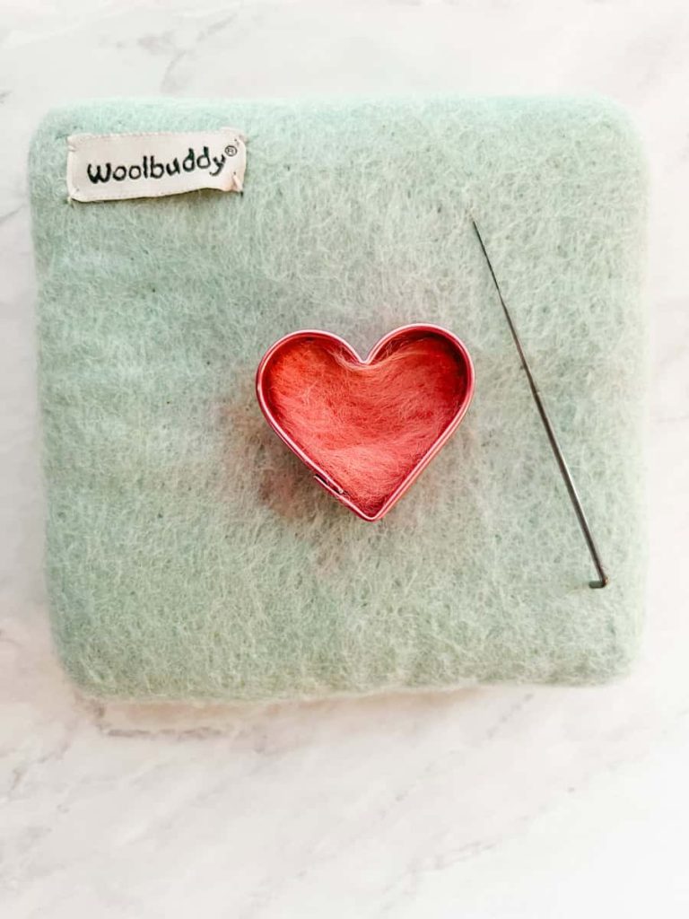 the back side of the heart ready to be felted inside the cookie cutter on the felting pad