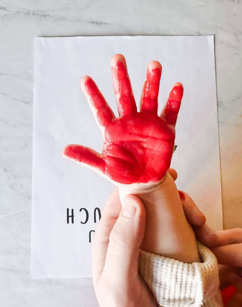 child's hand painted red with template behind it