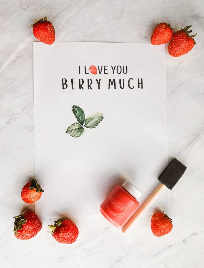 free printable "I love you berry much" template on table with paint, paint brush and strawberries around it