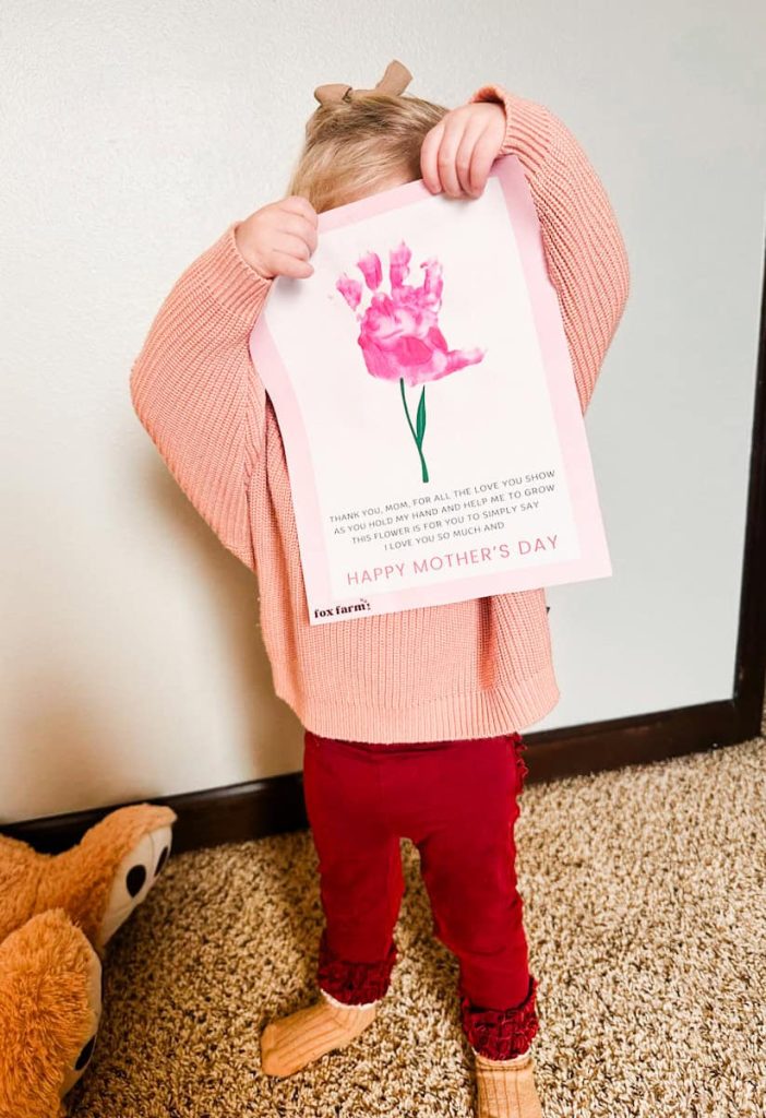 child holding up their completed mother's Day poem