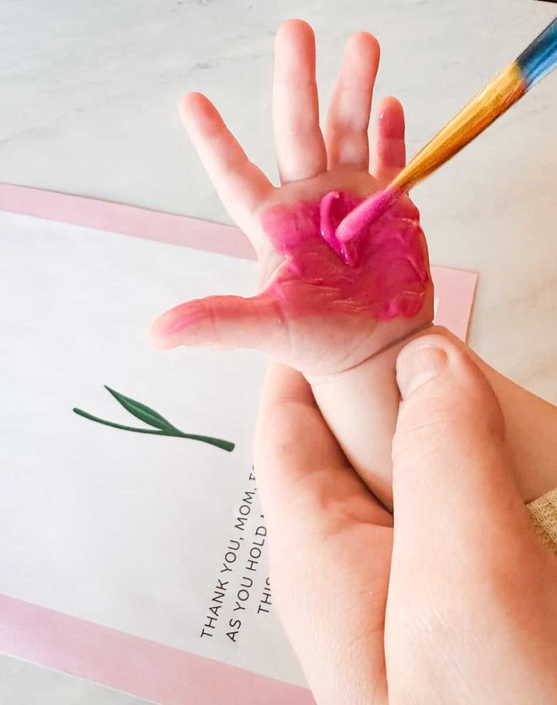 child's hand being painted with pink paint