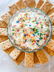 funfetti dip in bowl with graham crackers around it on a plate