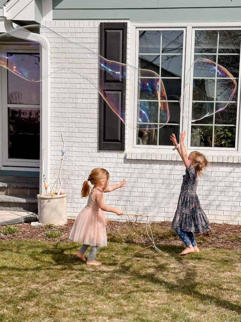 children chasing after large bubbles