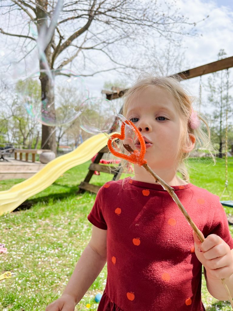 child blowing bubbles with a diy bubble wand from nature