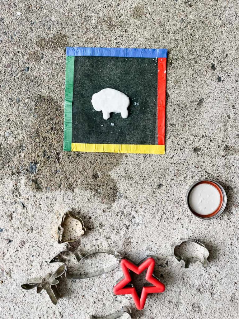 bison cookie cutter with seed paper in it on top of screen and cookie cutters on the ground around it