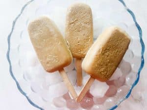 3 root beer float popsicles in a bowl over ice