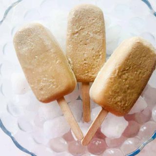 3 root beer float popsicles in a bowl over ice