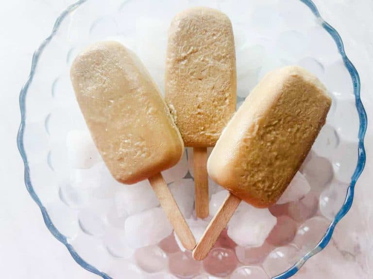 3 root beer float popsicles in a bowl over ice
