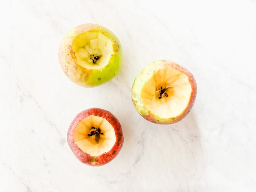 3 apples with the center scooped out on counter