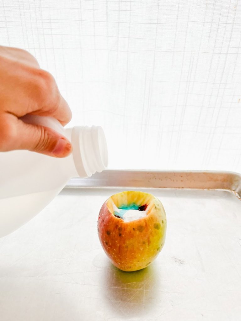 pouring vinegar into a prepared apple volcano
