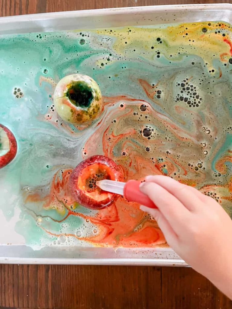 child playing with a pipette on a leftover apple volcano