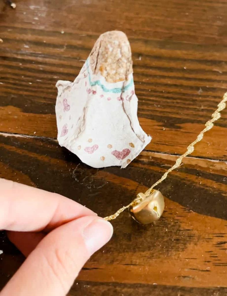 person stringing bell onto ribbon