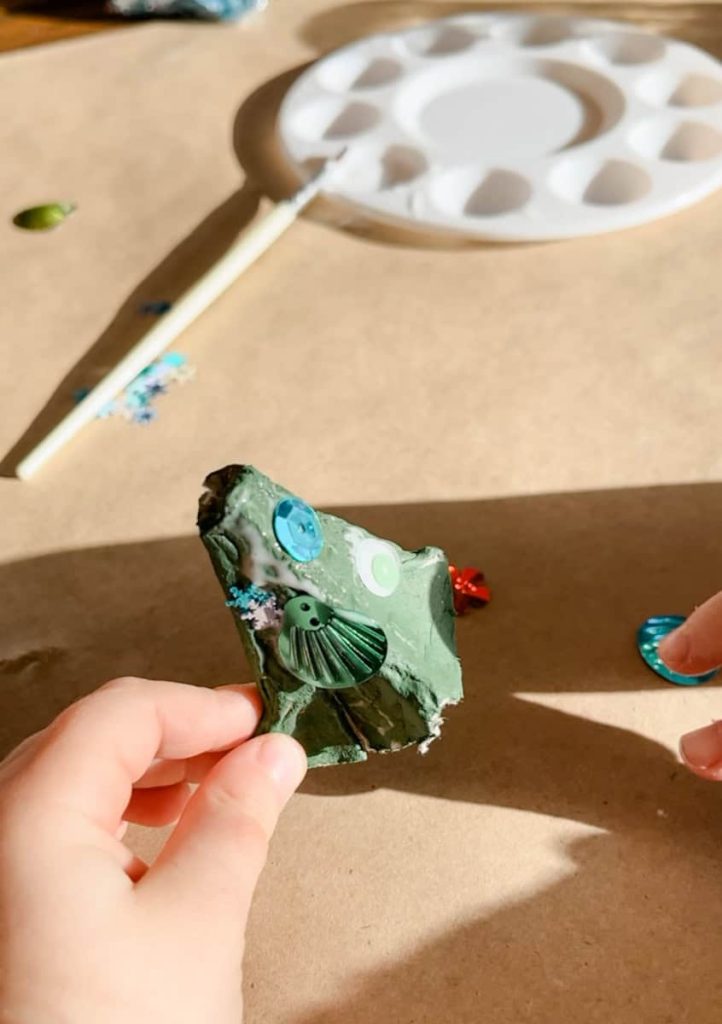 hands decorating the egg carton tree with sequins