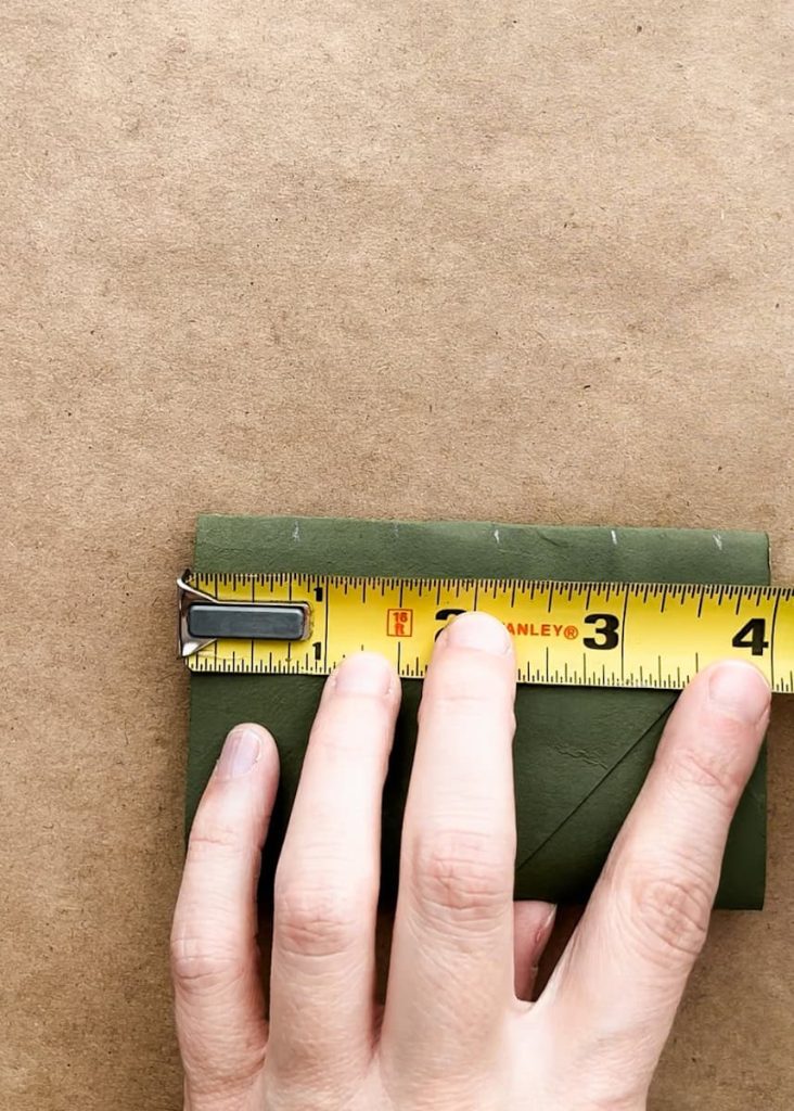 hand measuring .75 inches and marking it across a flattened tp roll