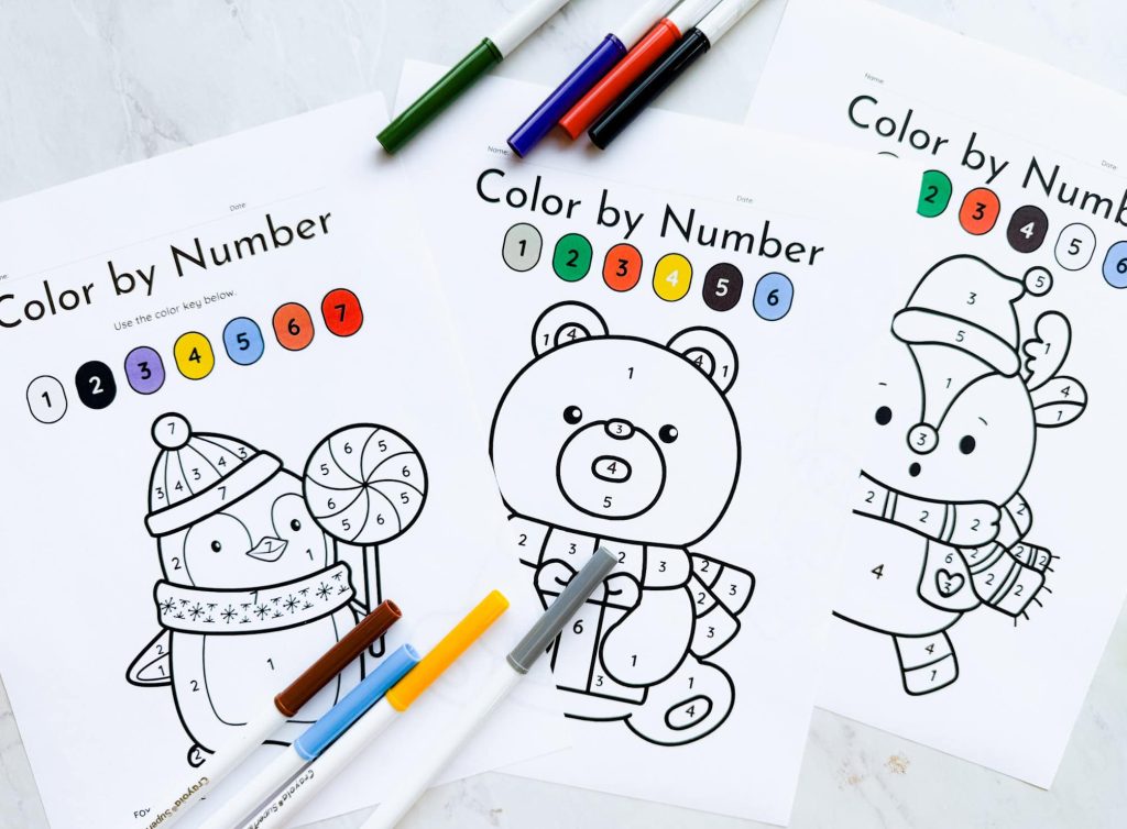 Blank color by number coloring sheets on table with markers around it