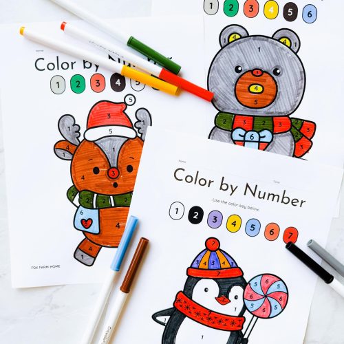3 color by number sheets completed on table with markers around them