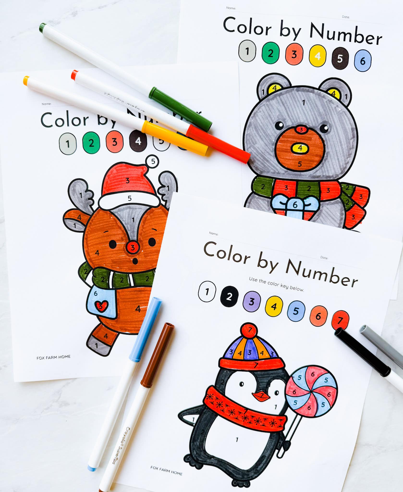 3 color by number sheets completed on table with markers around them