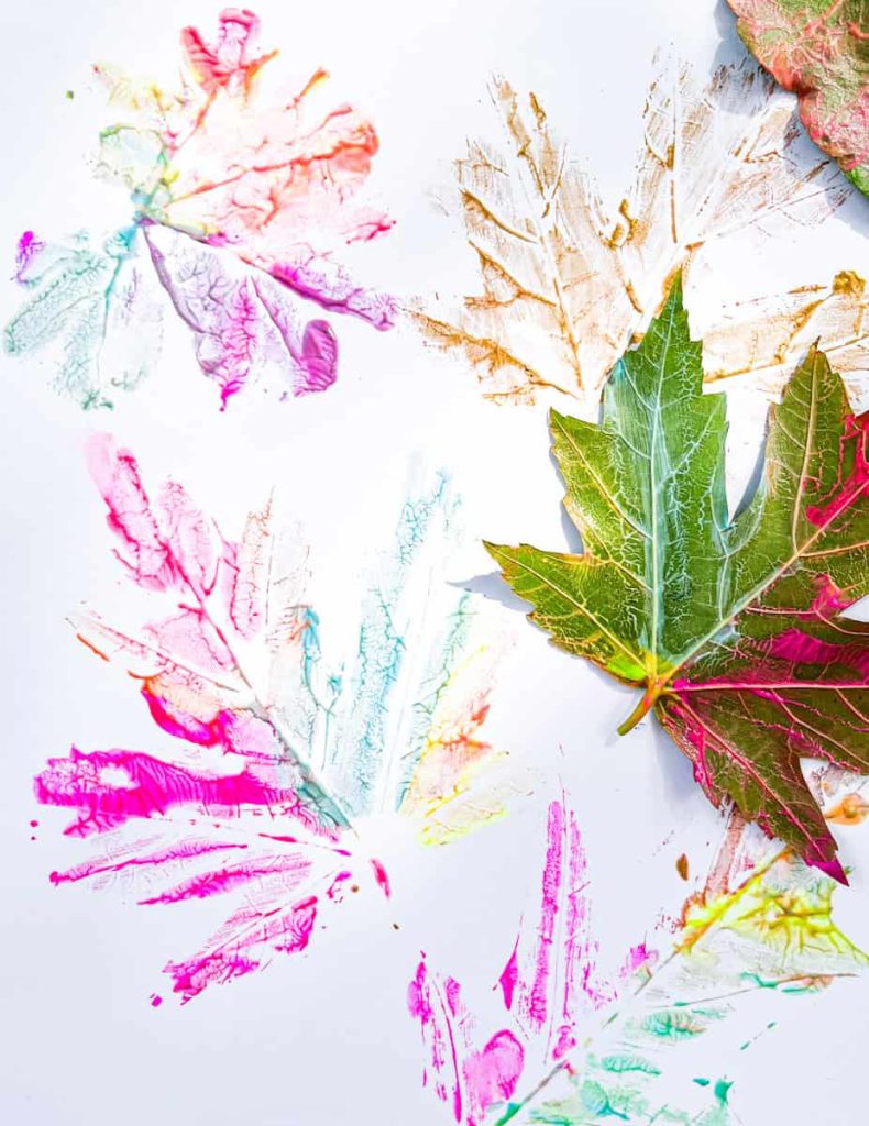 painted leaf next to paper filled with leaf prints