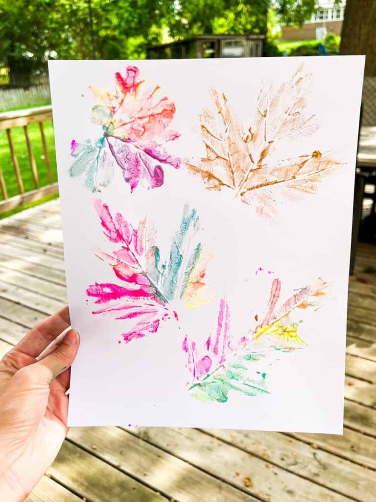 DIY leaf print held up in front of backyard