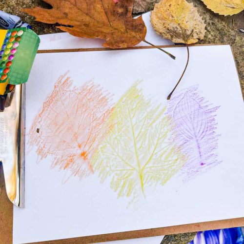 leaf rubbing on a clipboard with crayons and leaves around