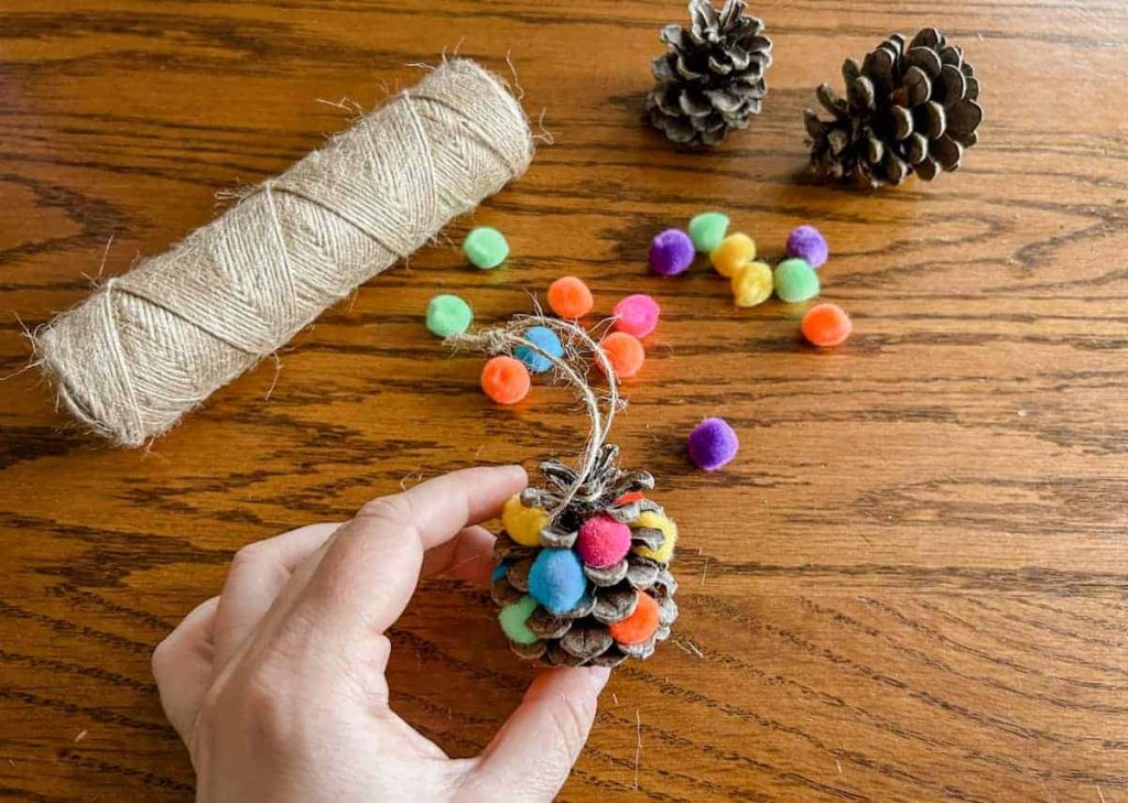 hand making a pom pom christmas tree craft