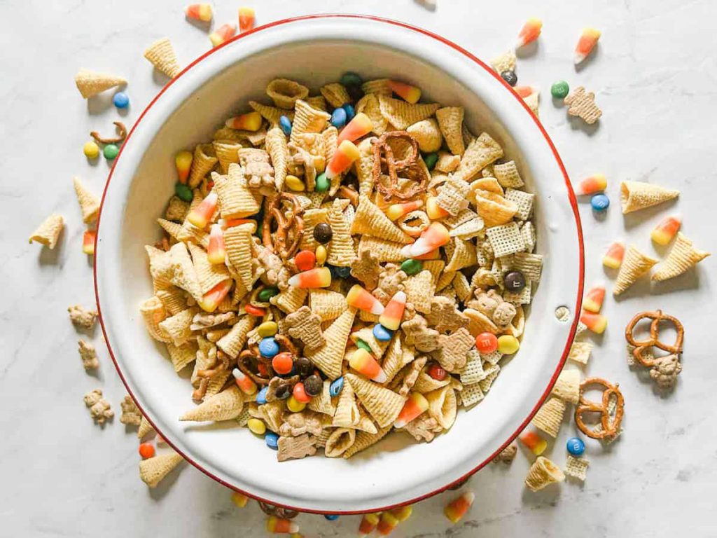Thanksgiving snack mix i a bowl with the mix on the table around the bowl as well