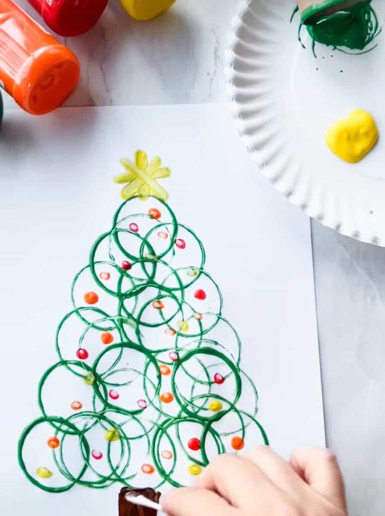 completed toilet paper Christmas roll tree with star on top and hand painting the grunk