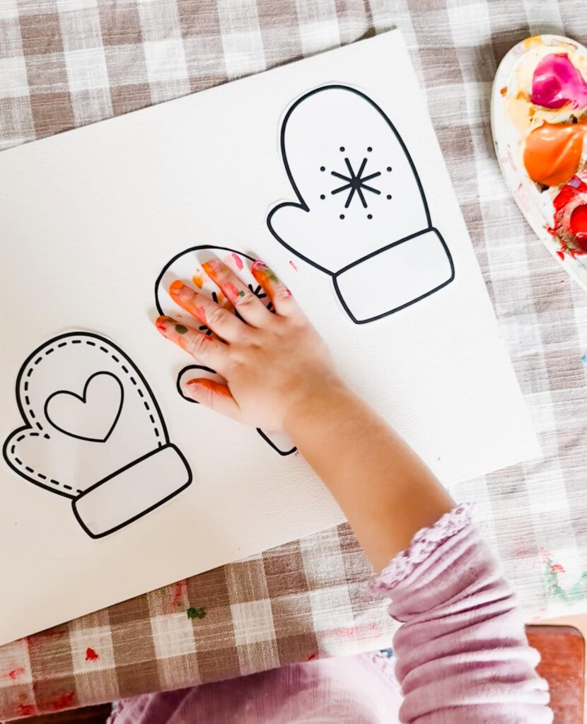 child putting their handprint on glove to paint it