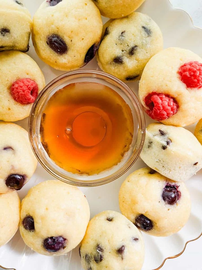 close up of mini muffins surrounding a glass bowl of maple syrup